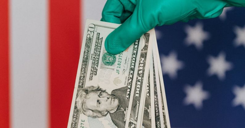 Trade Shows - Unrecognizable person wearing green latex glove showing heap of USA banknotes on blurred background of national flag of United States
